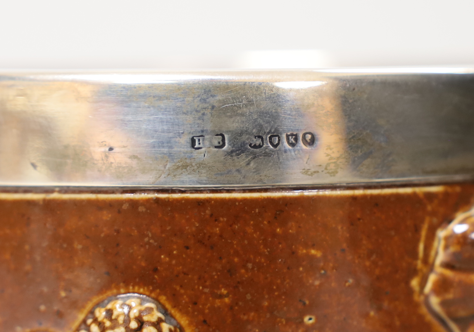 A Doulton Lambeth stoneware three handled tyg with silver collar, hallmarked London 1885, 18cm high